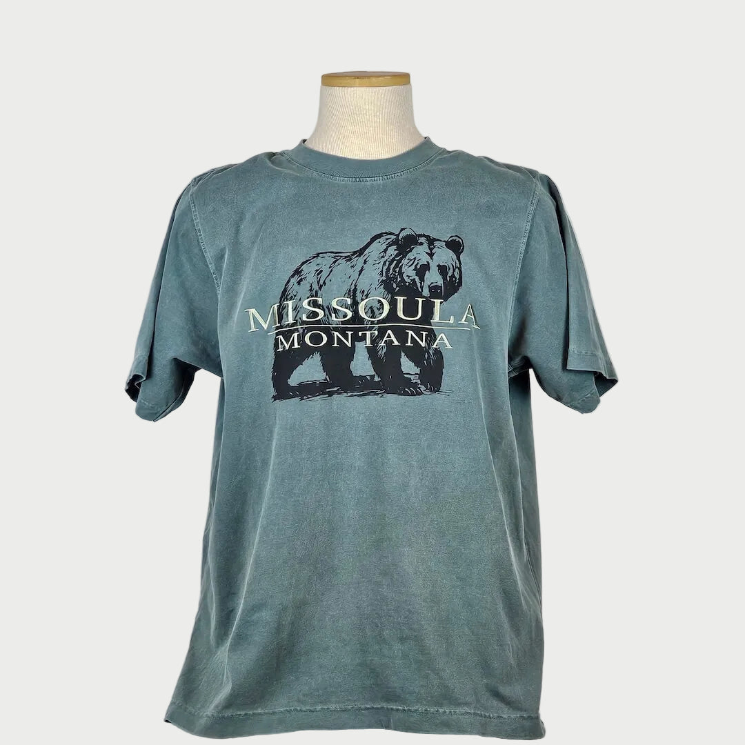 Blue t-shirt with a bear graphic and 'Missoula Montana' text on a mannequin against a gray background