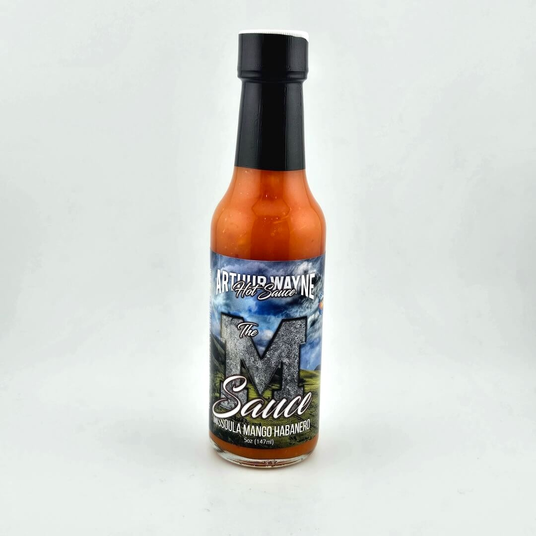 Glass bottle of hot sauce safety sealed with plastic. Label across main body of bottle details flavor and image depicting it.
