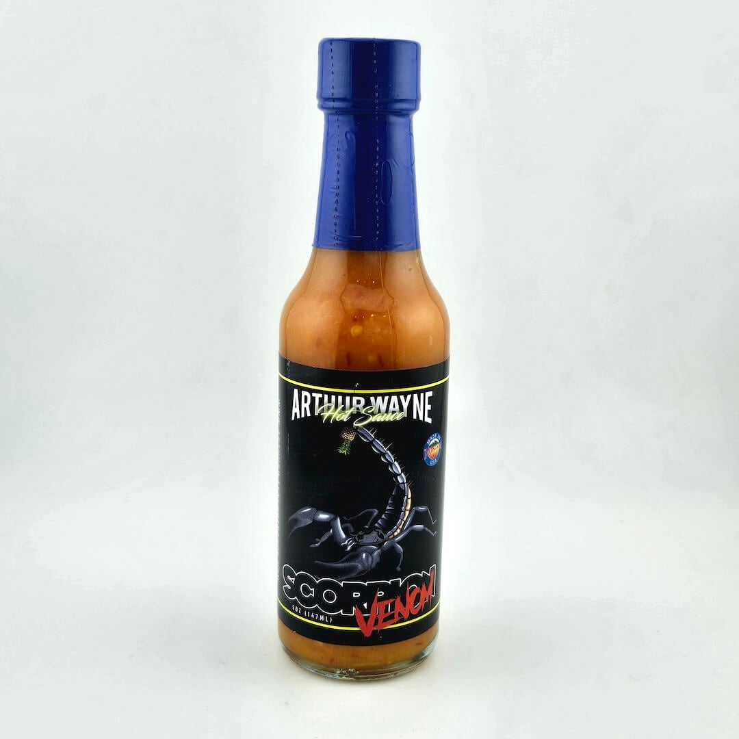 Glass bottle of hot sauce safety sealed with plastic. Label across main body of bottle details flavor and image depicting it.
