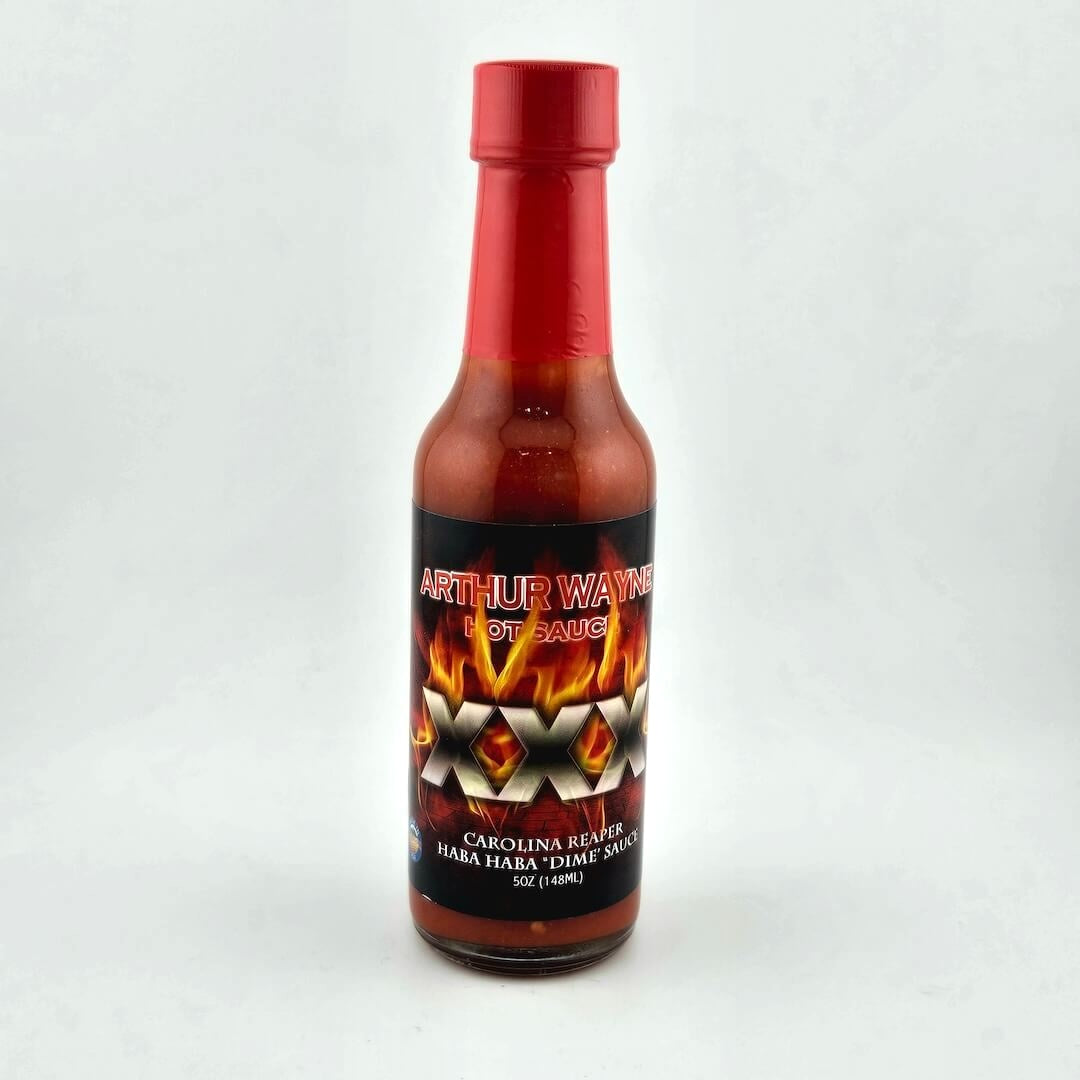 Glass bottle of hot sauce safety sealed with plastic. Label across main body of bottle details flavor and image depicting it.