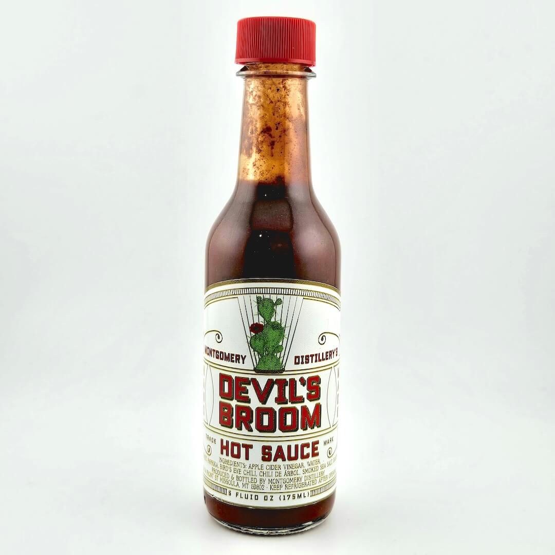 Bottle of Devil's Broom hot sauce with a red cap on a white background
