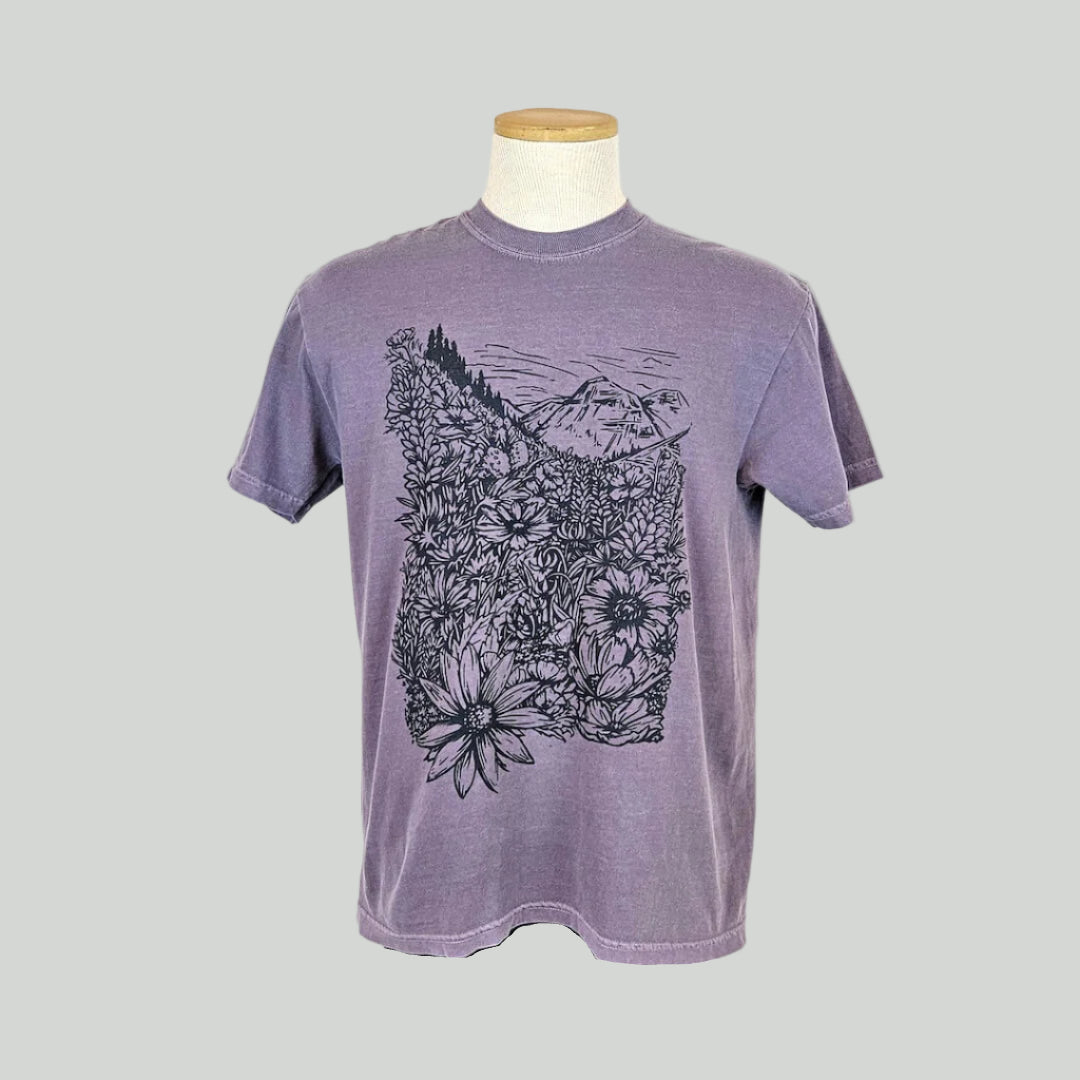Purple t-shirt with floral and mountain design on a mannequin against a white background