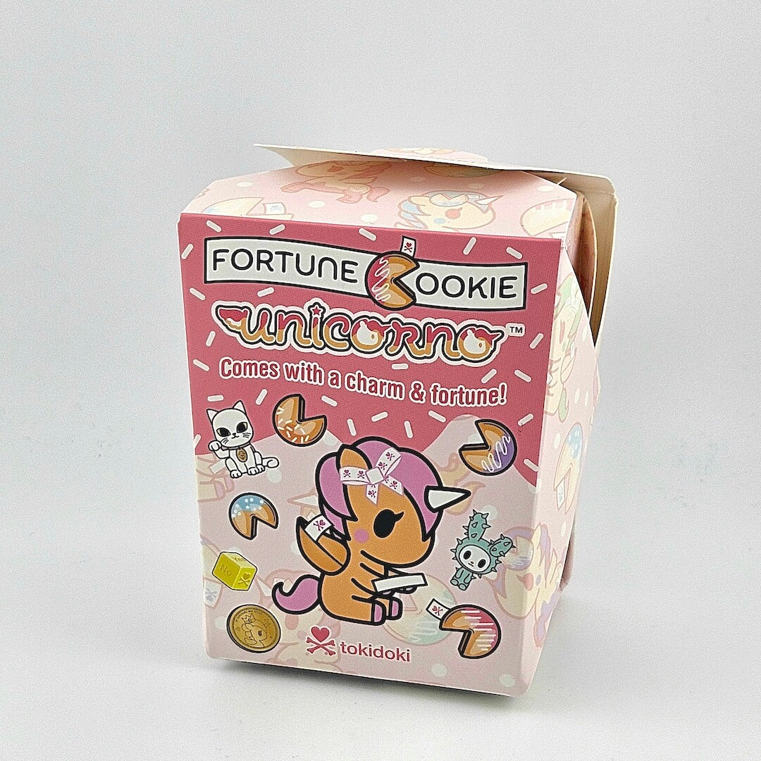 Brightly colored packaging for blind box unicorn figure against gray background.