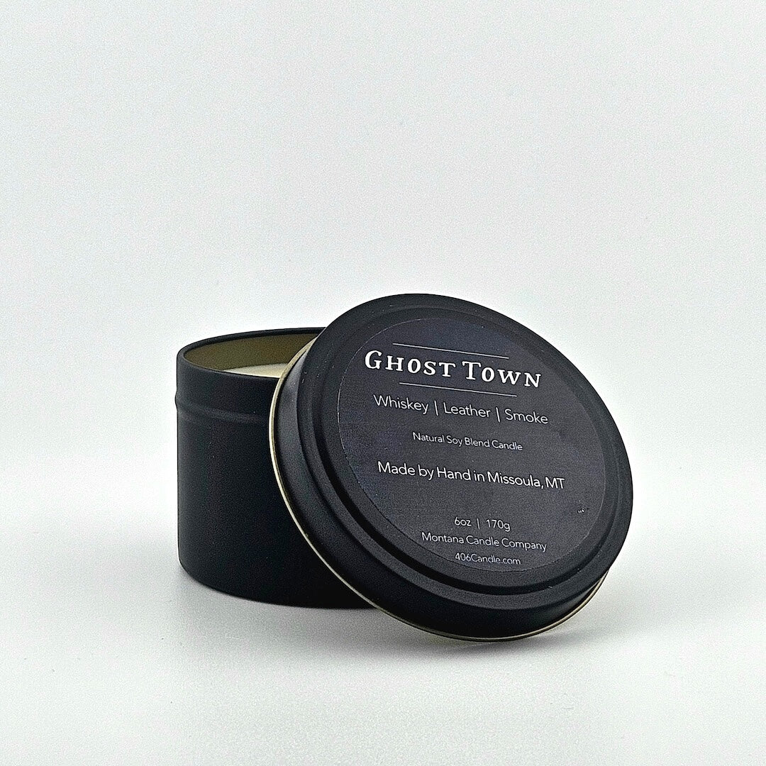 Black candle tin labeled with scent name, listed scent components, company & manufacturing information below.