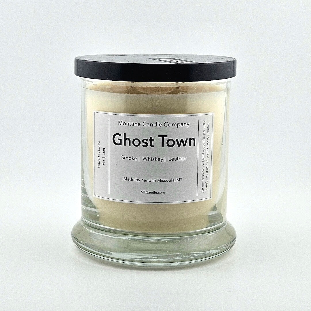 Glass jarred candle with black lid, label with printed company name top, scent name in center, then listed scent components.