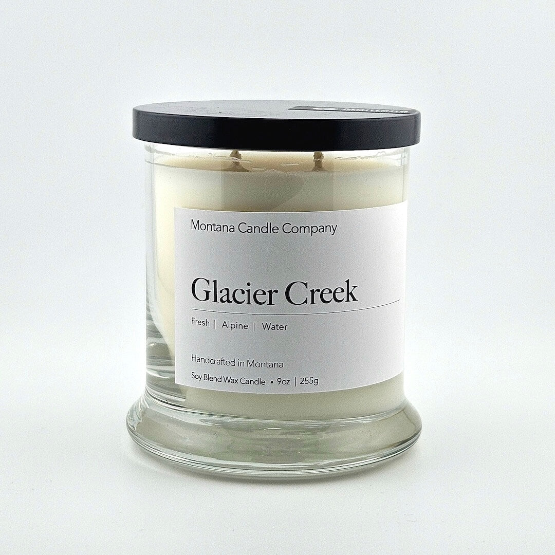 Glass jarred candle with black lid, label with printed company name top, scent name in center, then listed scent components.