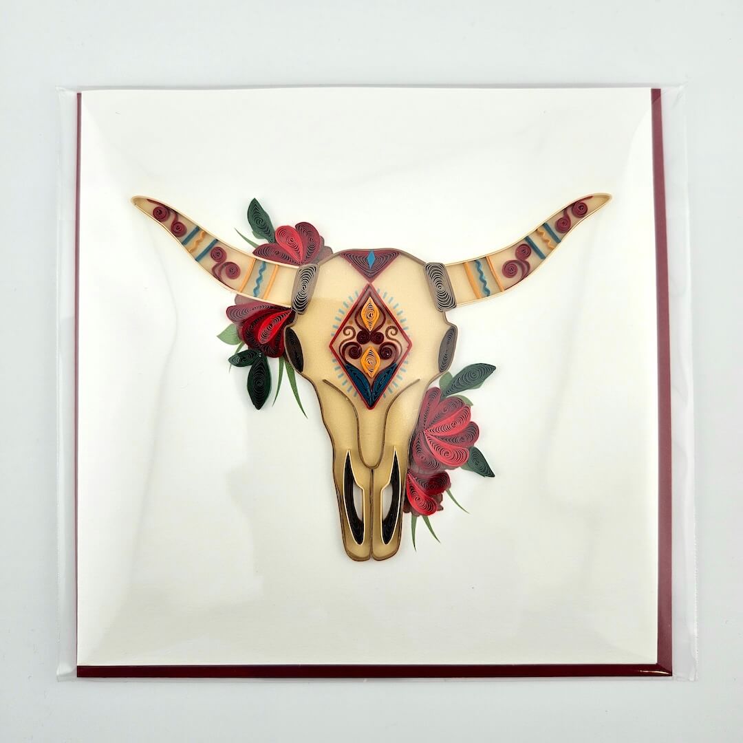 Decorative bull skull with floral elements and geometric patterns on a white background