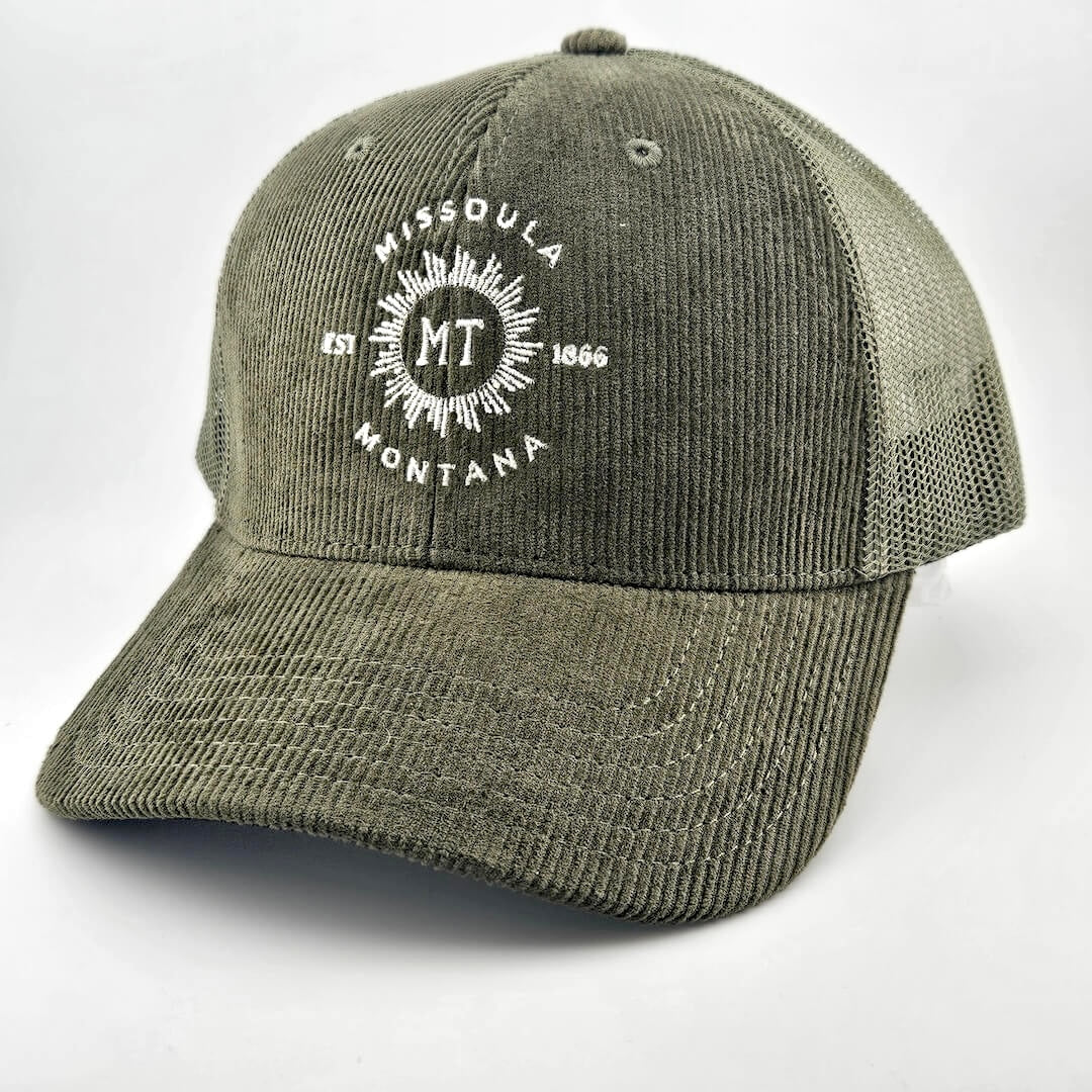 Green corduroy had with circular sunburst in center with "MISSOULA, MONTANA" encircling it with "MT" in center of sun.