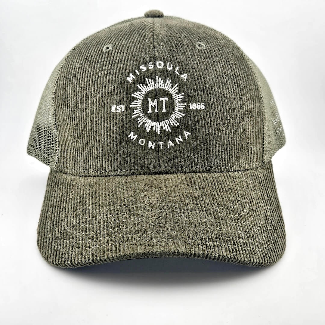 Green corduroy had with circular sunburst in center with "MISSOULA, MONTANA" encircling it with "MT" in center of sun.