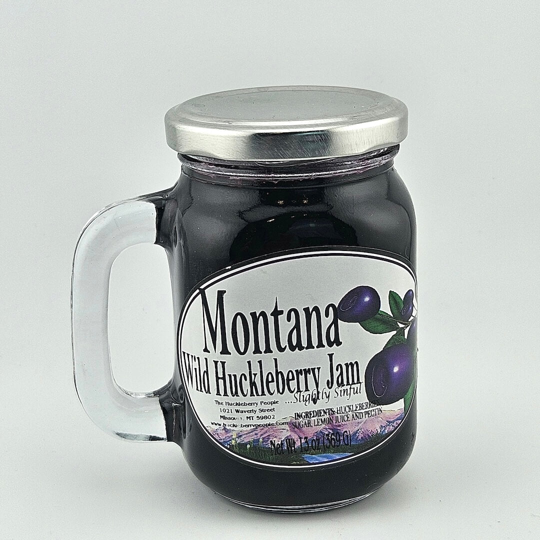 glass jar with handle and silver lid with label detailing product info in black print next enlarged huckleberry image.