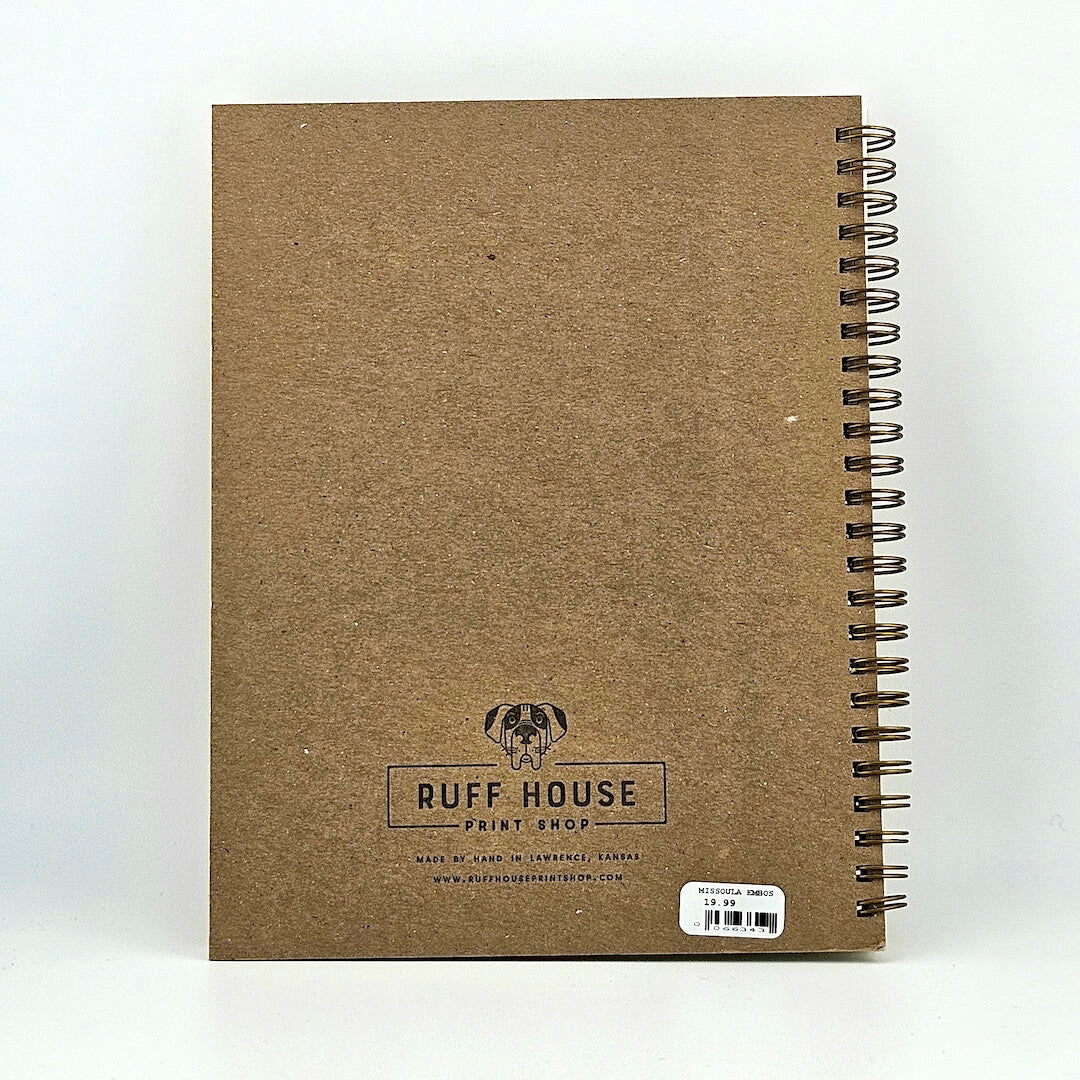 Cardboard backed spiral bound notebook against white background.