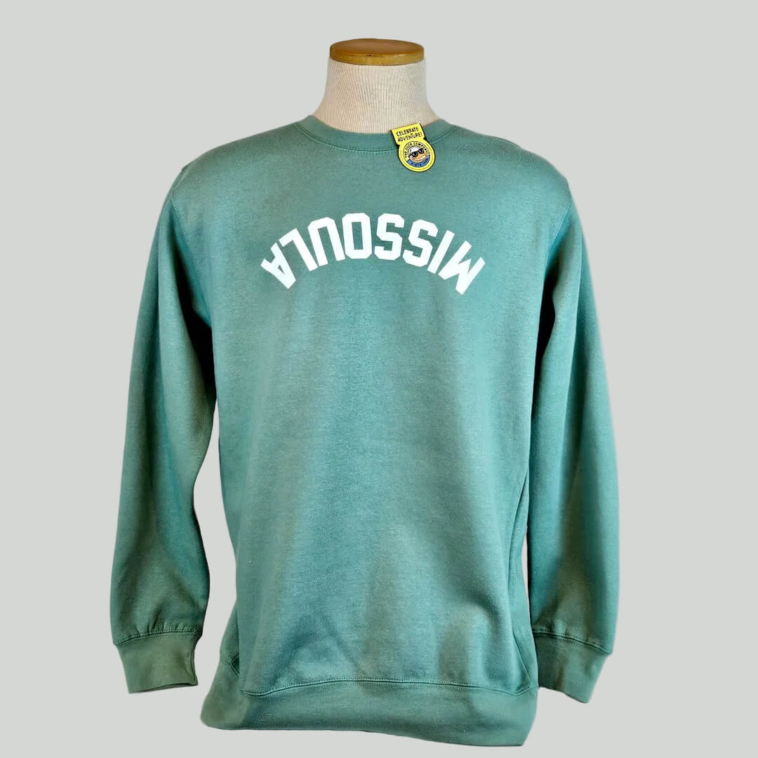 Green sweatshirt with 'MISSOULA' printed upside-down on it, displayed on a mannequin against a plain background.