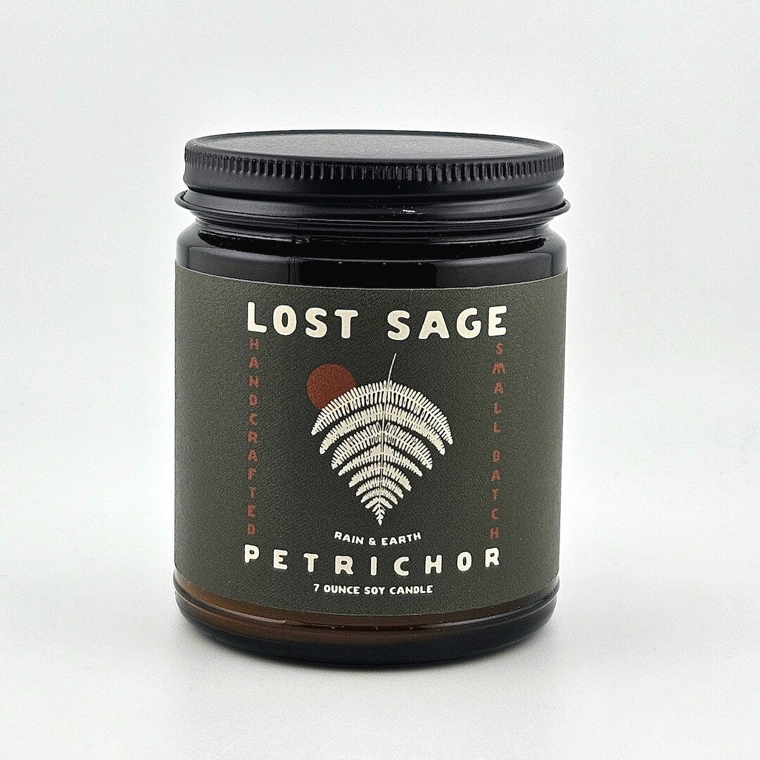 Candle jar labeled 'Lost Sage, Petrichor' on a white background