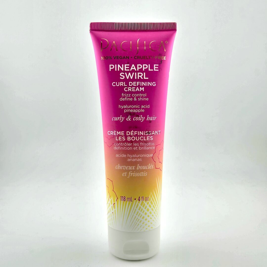 Squeeze bottle with pink and orange ombre and white text against white background.