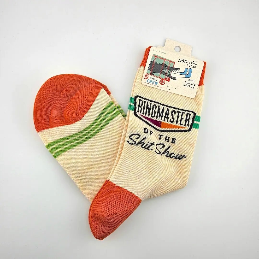 Beige sock with red toes and green stripes, featuring 'Ringmaster of the Shit Show' text, on a light gray background.