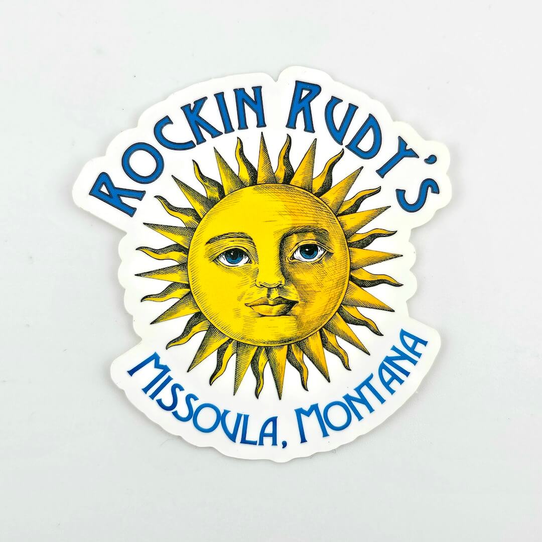 Sticker with sun design and text 'Rockin Rudt's Missoula, Montana' on a light gray background