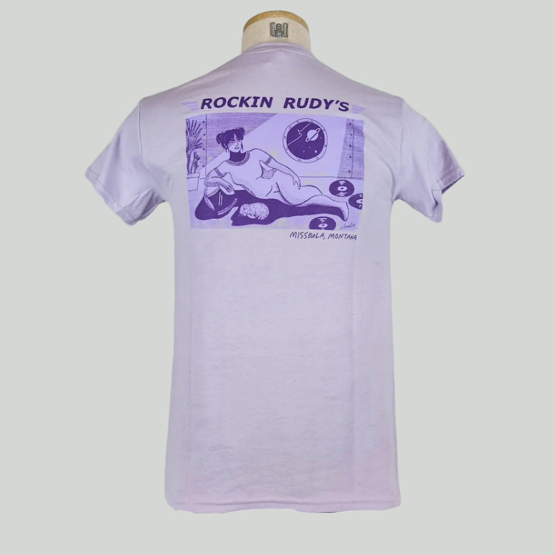 Lavender t-shirt with girl in space suit laying down by cat and scattered records with porthole showing planet & stars.