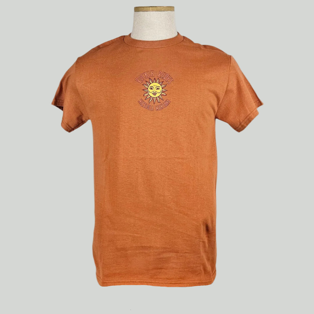 Orange colored t-shirt with small sun in center with "ROCKIN RUDY'S" & "MISSOULA, MONTANA" encircling it.