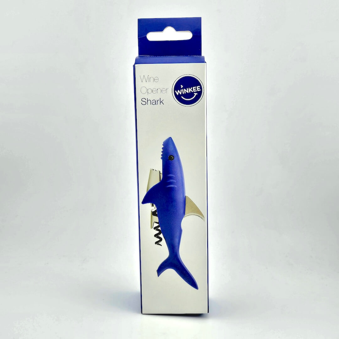 Blue and white packaging for shark shaped bottle opener against white background.