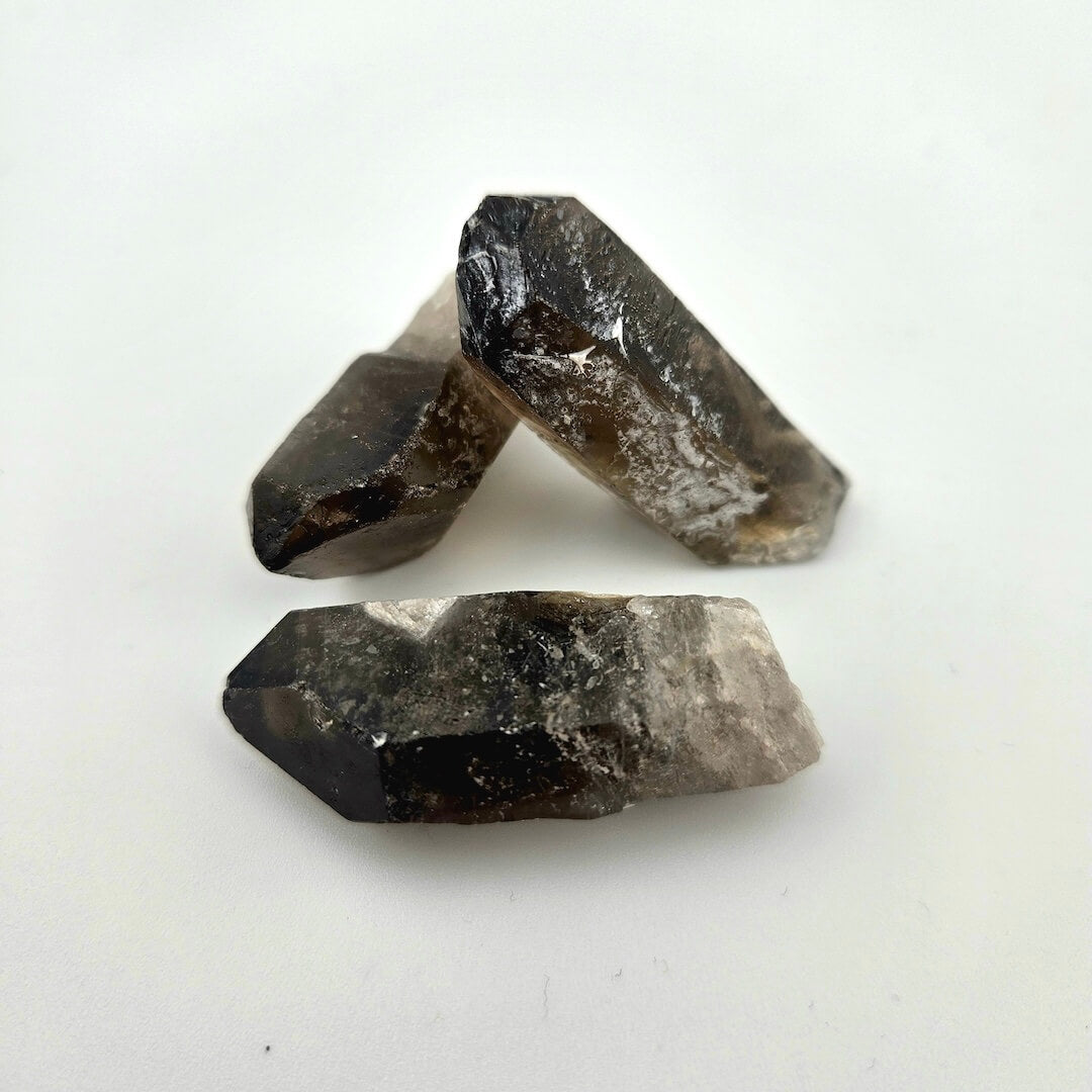 Three gray and dark brown crystal stones on a white background