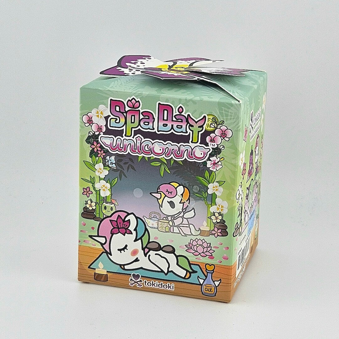Brightly colored packaging for blind box unicorn figure against gray background.