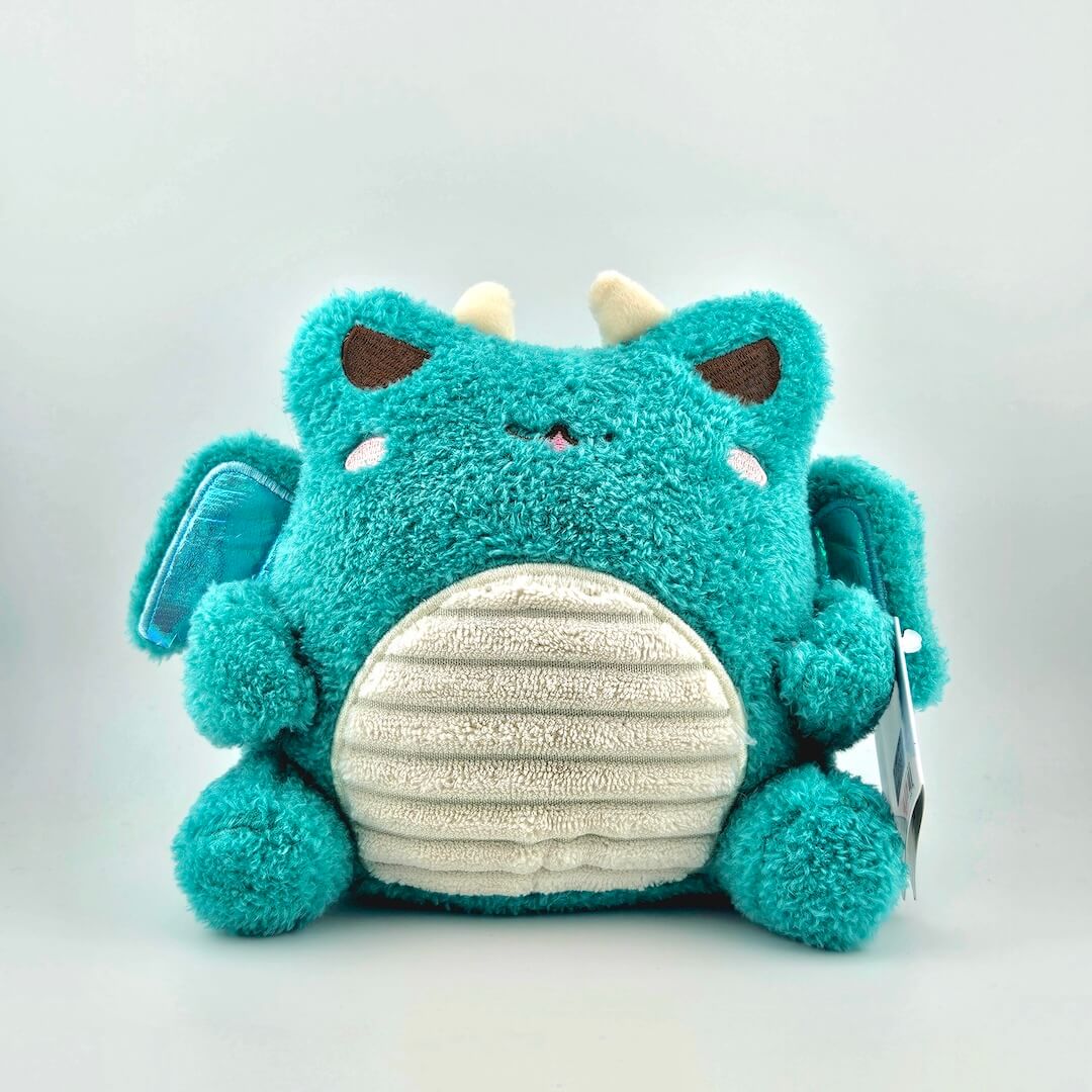 Teal winged plush animal with horns, and tag against white background.
