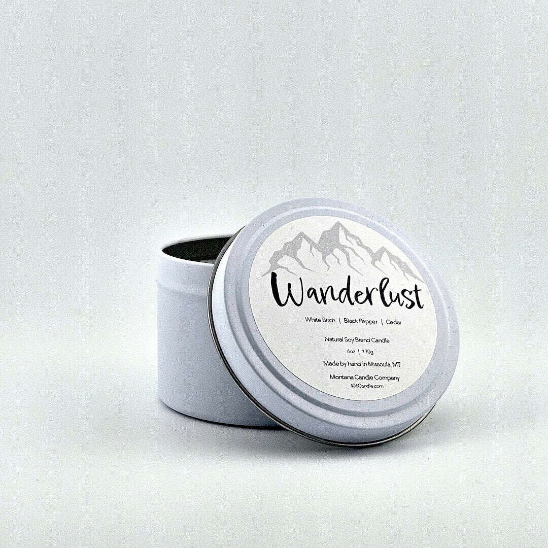 Metal tin candle label with label with gray mountain silhouette above printed script name above scent components.