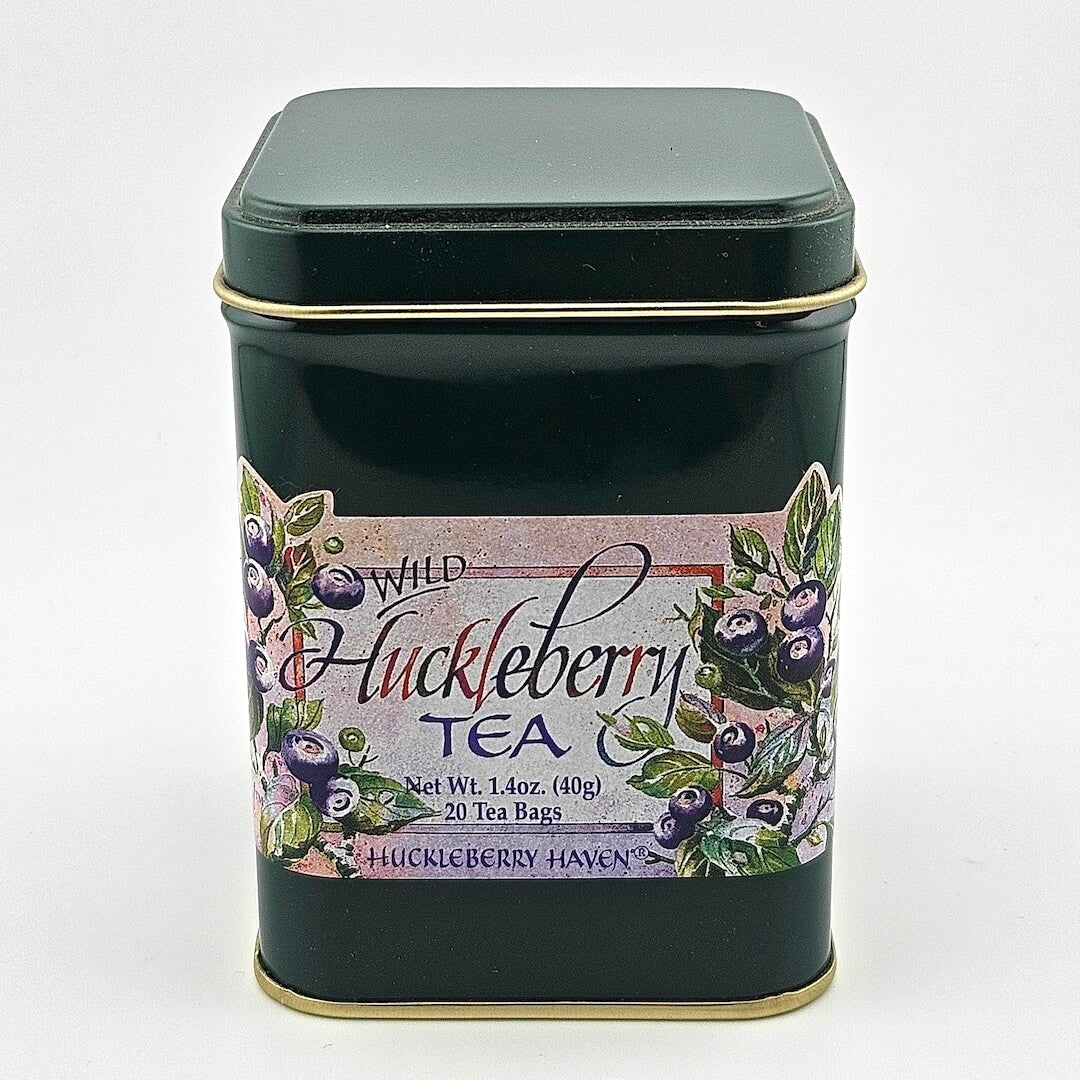Dark green metal tin with label featuring painting of huckleberries framing product information.