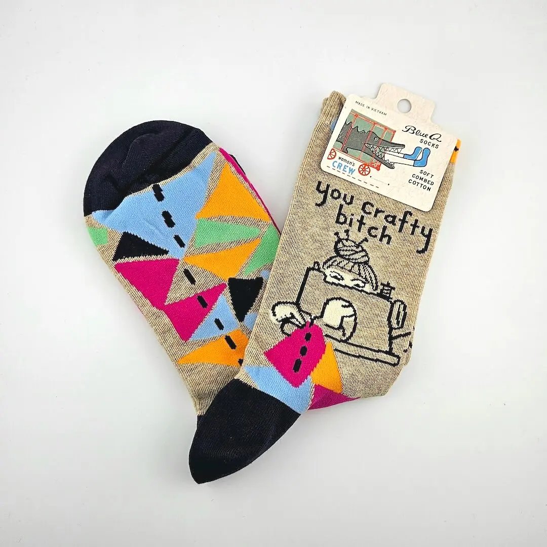 Colorful geometric-patterned sock with a humorous text design on a plain background