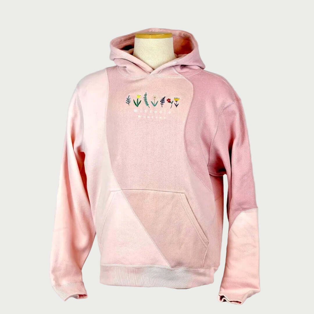 Pink hoodie with floral designs on a mannequin against a plain background