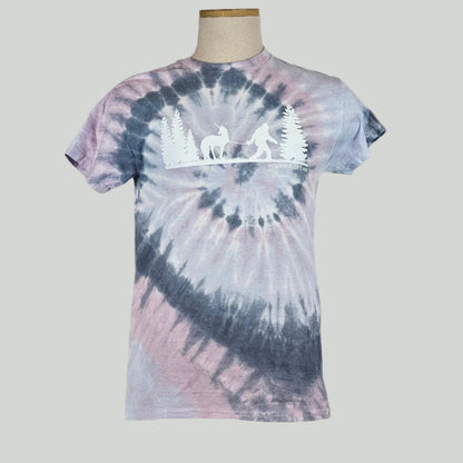 Lavender & navy tie Dye shirt with silhouette of trees either side of Bigfoot leading a unicorn on a leash. 