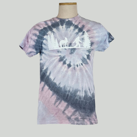 Lavender & navy tie Dye shirt with silhouette of trees either side of Bigfoot leading a unicorn on a leash. 