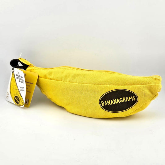 Yellow fabric bag shaped like a banana. Brown loop with paper tag at top corner. "Bananagrams" printed at tip in oval. 