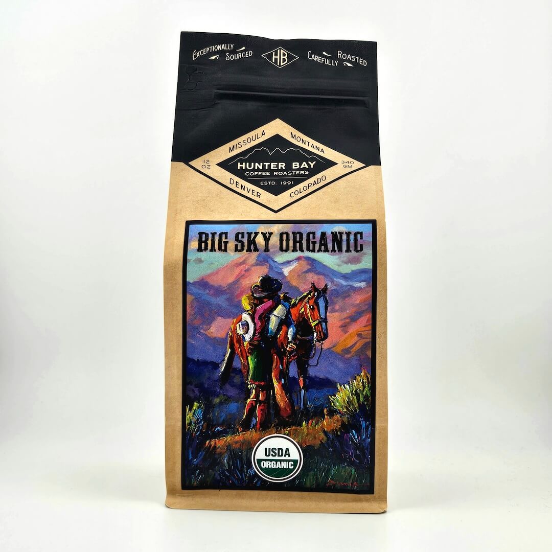 Coffee bag with 'Big Sky Organic' design featuring a person on horseback against a mountainous landscape.