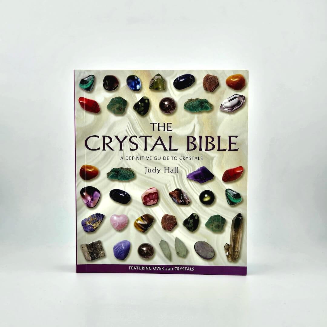 Book titled 'The Crystal Bible' by Judy Hall with images of crystals on a white background
