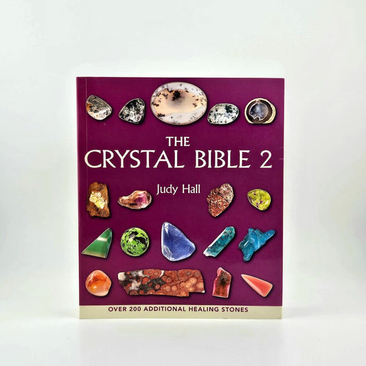 Book titled 'The Crystal Bible 2' by Judy Hall with images of crystals on a purple background.