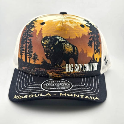 Trucker hat with mountain landscape across face with bison as central image. Missoula, Montana embroidered across bill. 