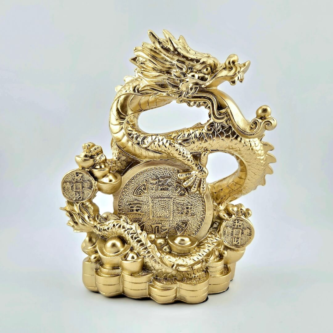 Gold dragon figurine with coins on a light gray background