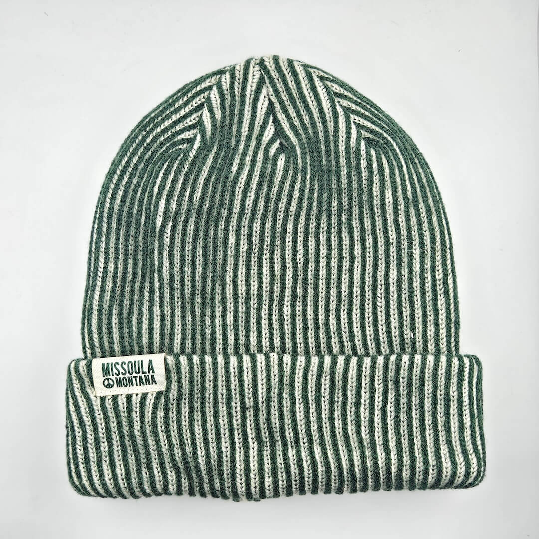 Green and white striped beanie with a label on a light gray background