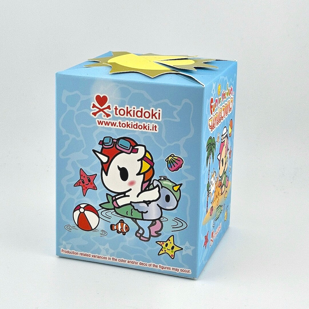 Brightly colored packaging for blind box unicorn figure against gray background. 