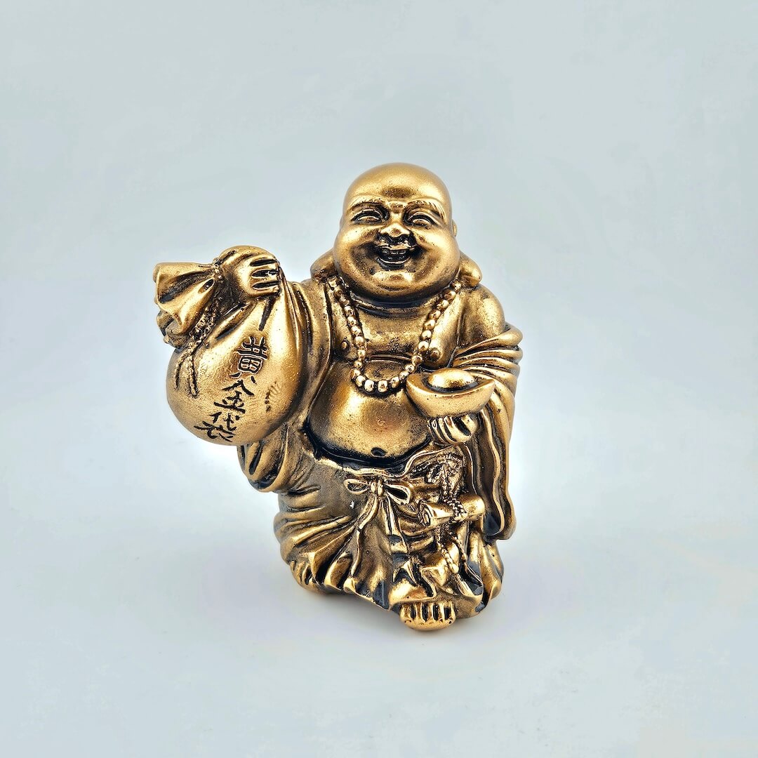 Gold Buddha figurine holding a bag on a light gray background