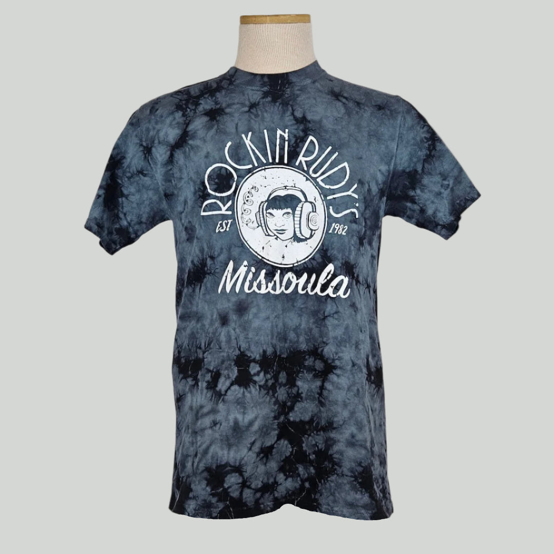 Black & gray tie dye t-shirt with center image is girl wearing headphones with "ROCKIN RUDY'S" above, "Missoula" below. 