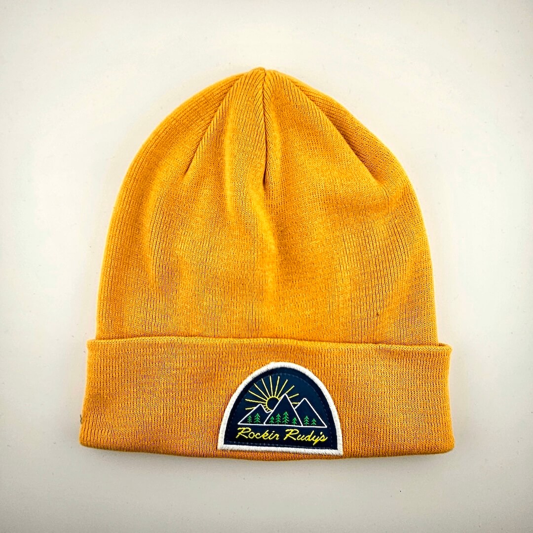 Yellow beanie with a logo patch on cuff for Rockin Rudy's on a light gray background