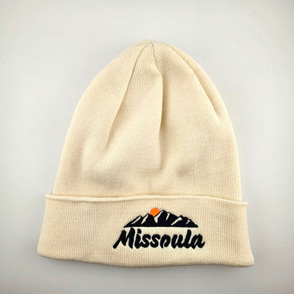 Beige beanie with 'Missoula' and mountain design on a gray background