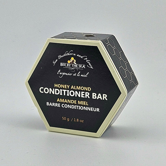 Hexagonal container of Honey Almond Conditioner Bar by Bee by the Sea on a gray background