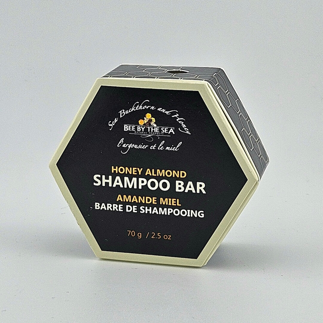 Hexagonal packaging of a honey almond shampoo bar with branding on a light gray background