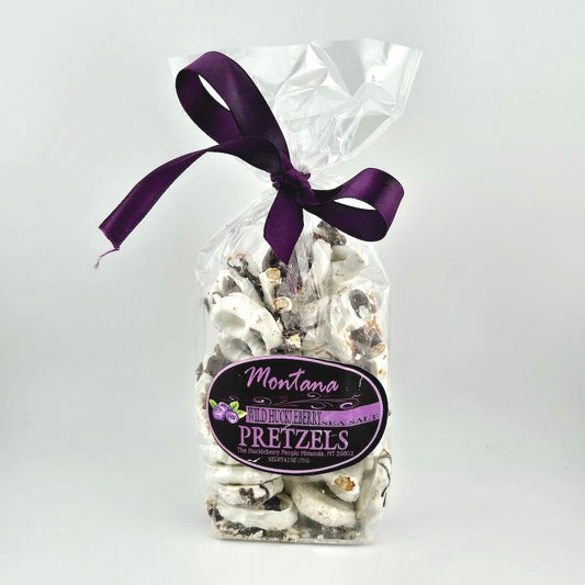 Bag of pretzels with a purple ribbon and 'Montana Buckwheat Pretzels' label on a white background