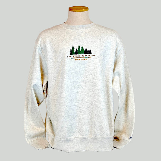 White sweatshirt with 'In the Woods Montana' logo on a mannequin against a white background