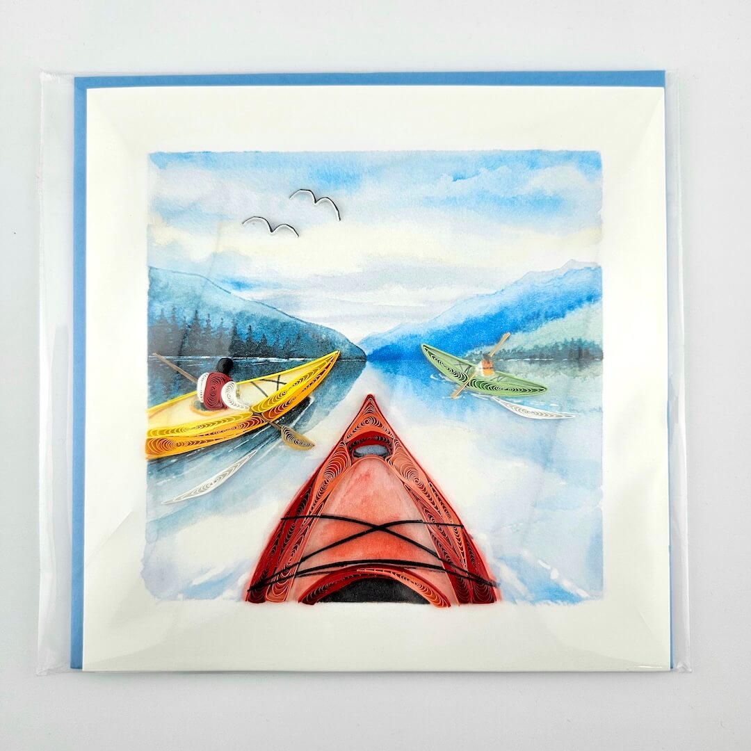 Quilled artwork of kayaks on a watercolor landscape with mountains and sky.