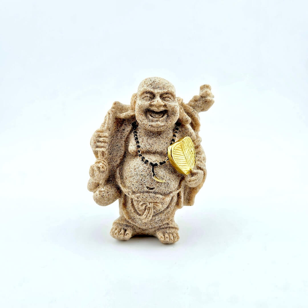 Statue of a laughing Buddha holding a gold leaf on a white background